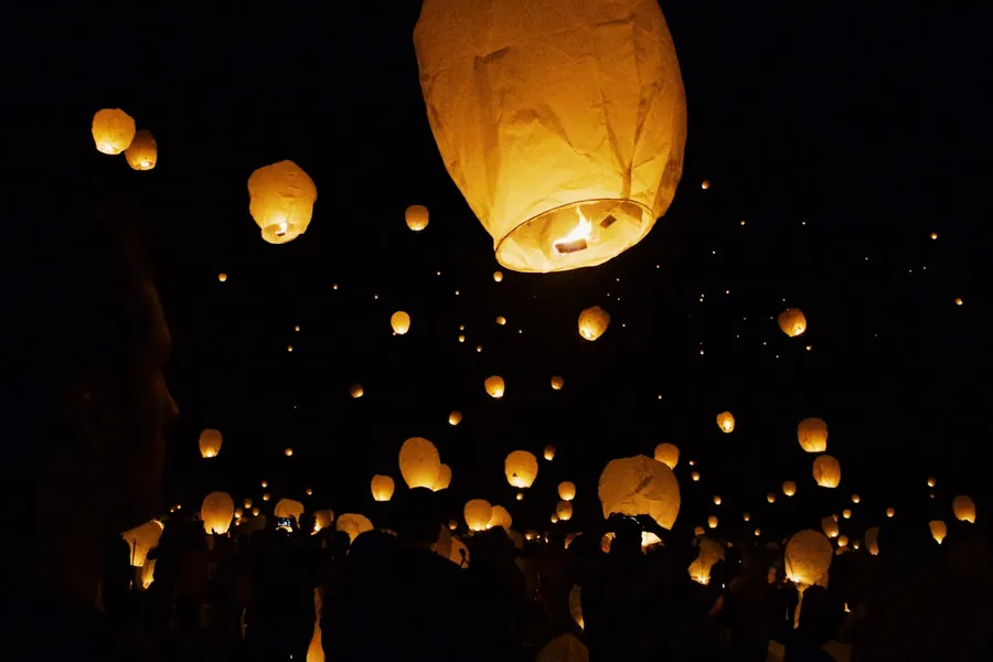 Globo de cantoya iluminado elevándose en el cielo nocturno sobre Hotel Onsen